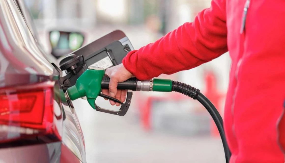 Red jumpered man putting petrol in car