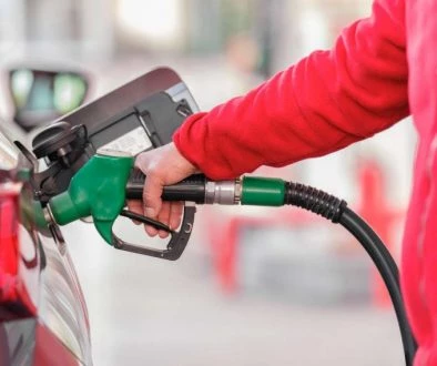 Red jumpered man putting petrol in car